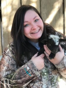 teen girl with braces holding goat