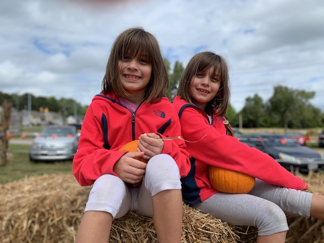 双子の女の子が干し草の山に微笑んでいる